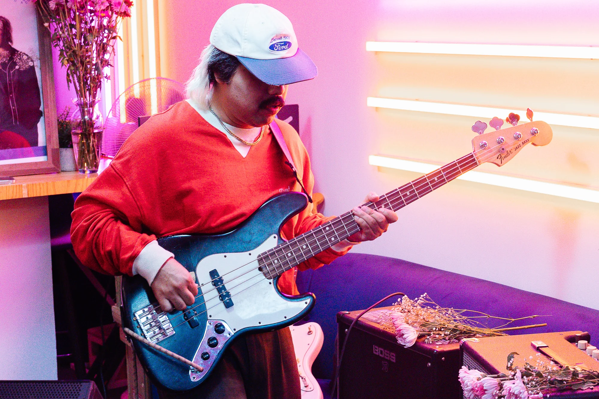 The bassist playing under pink stage light, photographed by Ludovic Delot