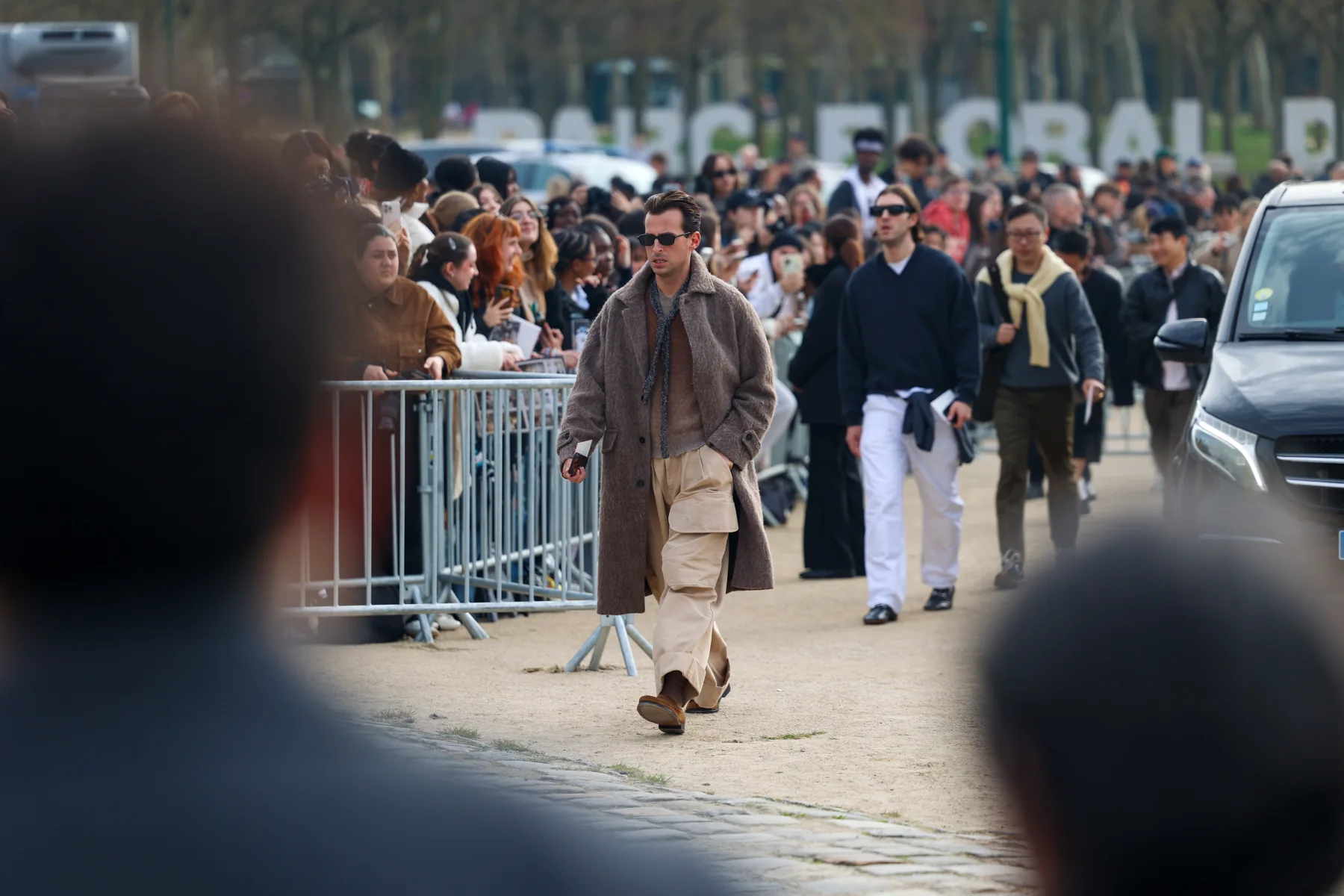 Wide establishing view of the street and arrivals around the LOEWE FW26 show in Paris, photographed by Ludovic Delot
